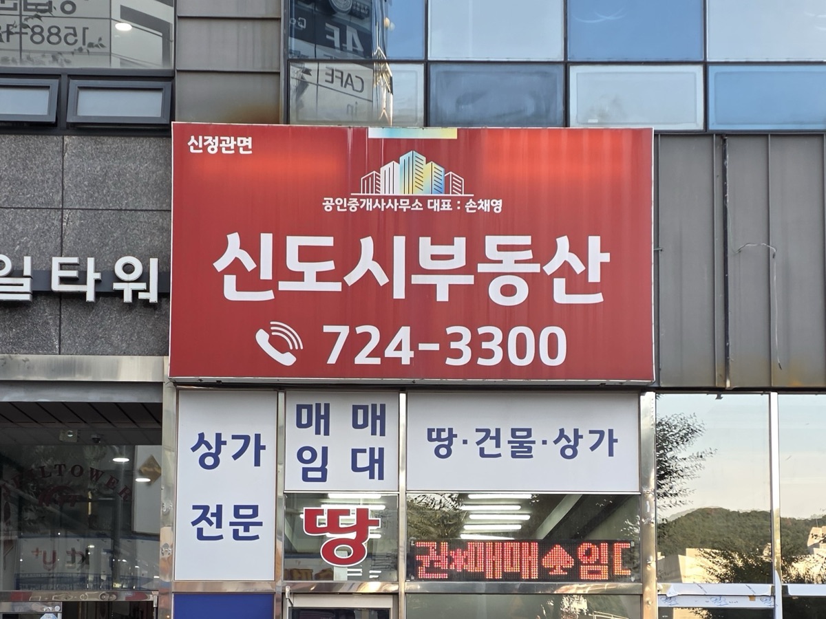 정관 제일타워 신도시부동산 간판. 상가·땅·건물 매매·임대 전문, 전화 724-3300